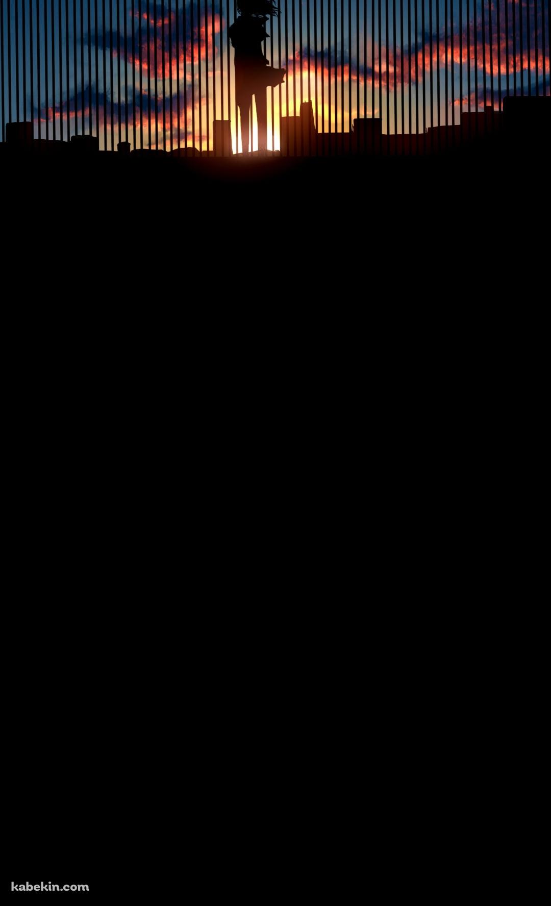 ビルの屋上の柵越しから夕陽を眺める女性のAndroidの壁紙(1080px x 1776px) スマホ用