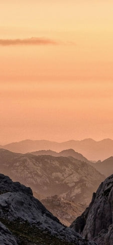 淡いオレンジの夕日と山のiPhone / スマホ壁紙