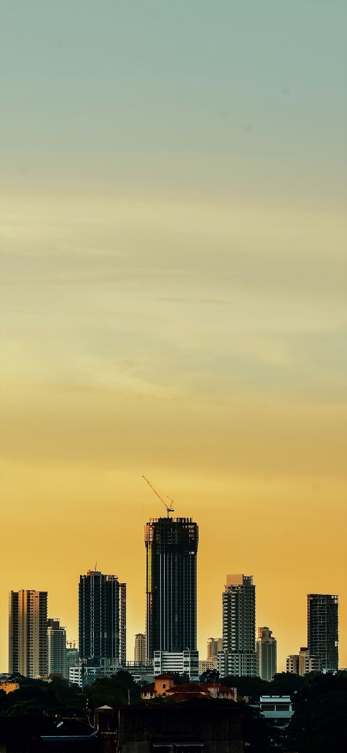 高層ビルとクレーンと黄色の空の1170 x 2532 / スマホ壁紙