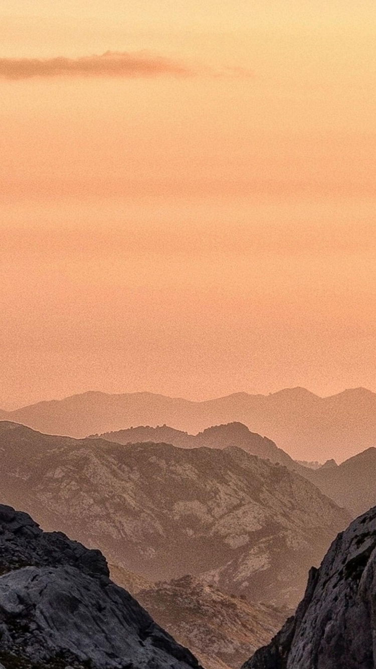 淡いオレンジの夕日と山の750 x 1334 / スマホ壁紙