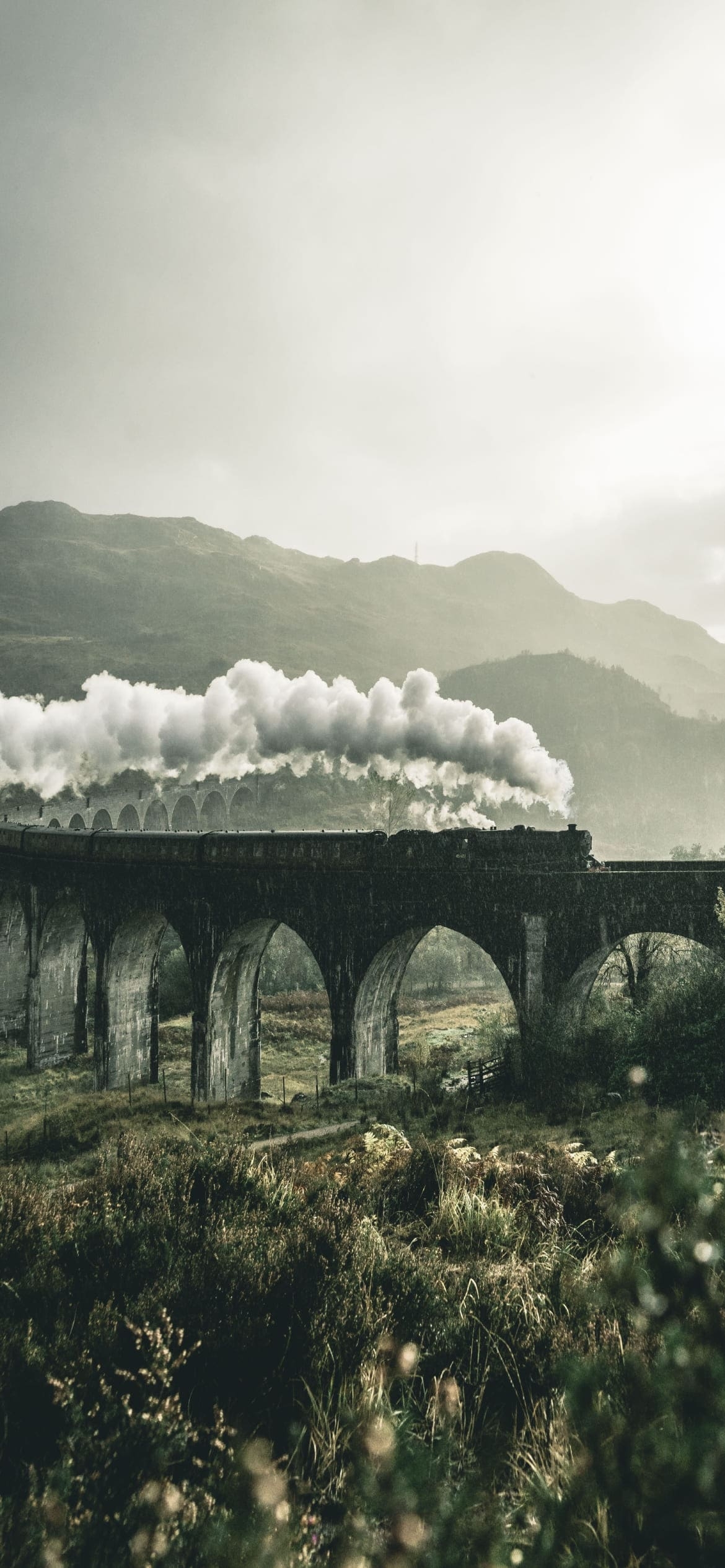 グレンフィナン高架橋を通過する汽車 / ウェスト・ハイランド線の鉄道高架橋 / スコットランド北西部 / ハイランドの1170 x 2532 / スマホ壁紙